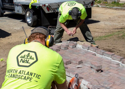 Hardscape installation team laying brick walkway.